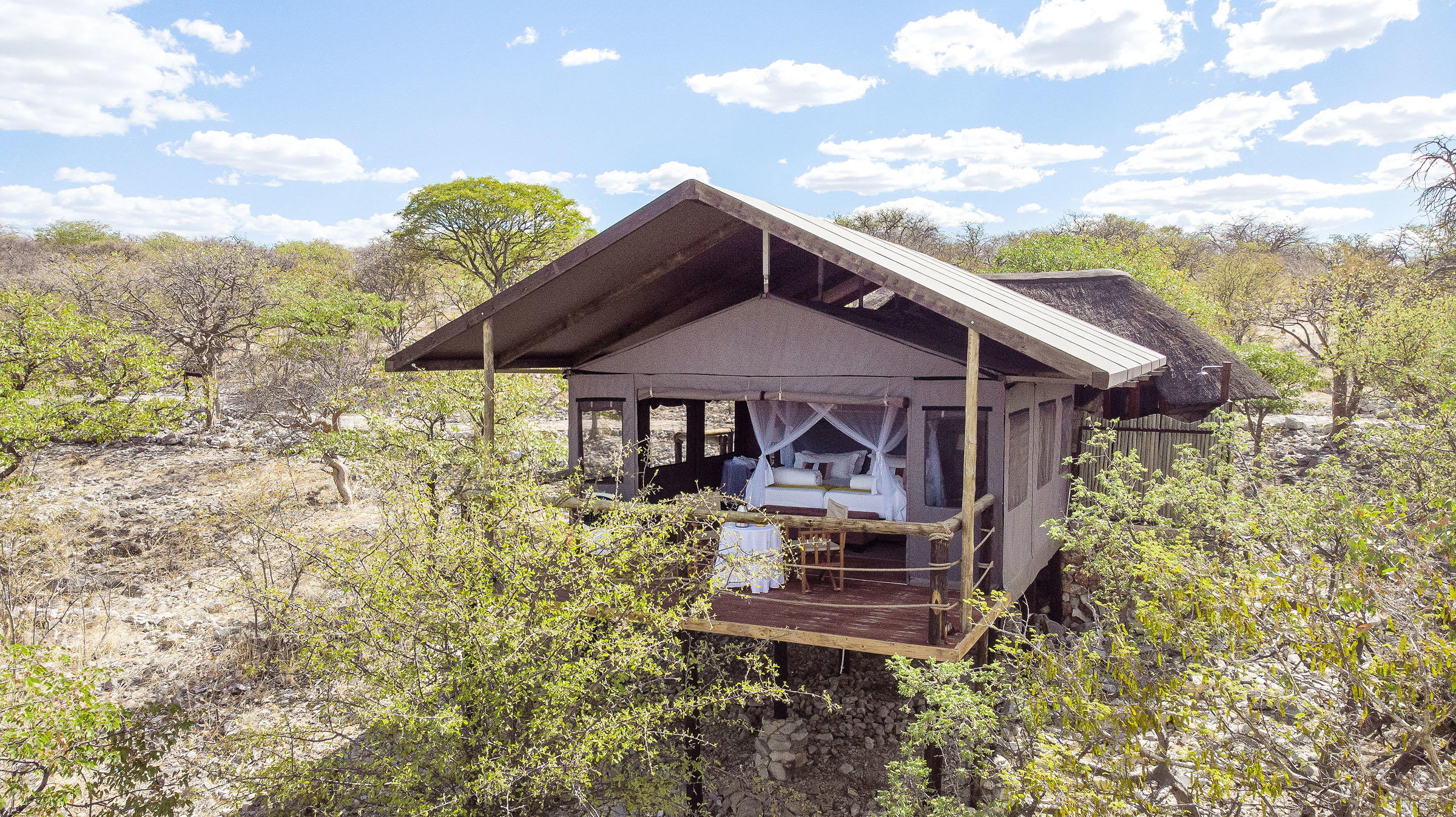 Exterior view of a luxury canvas safari tent nestled in the hills